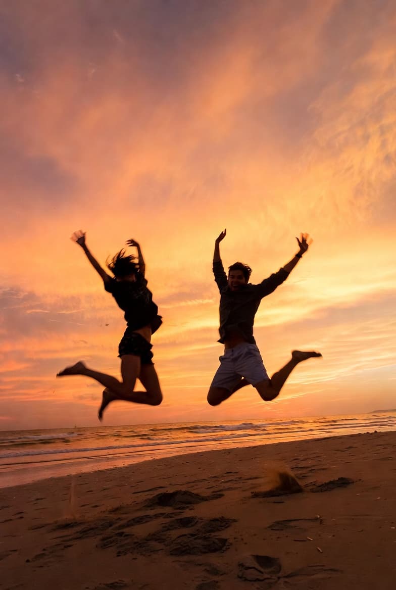 Friends jumping on beach at sunset